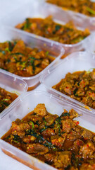 Clear plastic containers filled with a savory meat stew, garnished with herbs and chili flakes. Perfect for meal prep and food storage visuals.