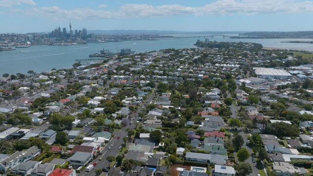 Aerial view of Auckland, New Zealand's residential suburbs, showcasing diverse housing styles and lush greenery. Cityscape and harbor visible in the background. Devonport, Auckland, New Zealand