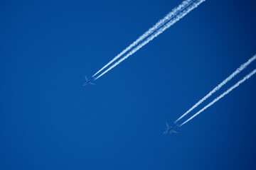Airplane in the blue sky with contrail. Two planes in the sky.