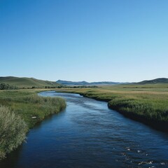 Serene river flowing through a vast green meadow under a clear blue sky.