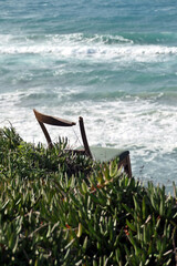 Fototapeta premium Wooden chair on the edge of a cliff by the sea. Abandoned wooden chair on the shore of the Mediterranean Sea in Israel.