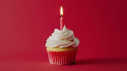  a single cupcake with white frosting and a lit birthday candle, set against a solid red background. 