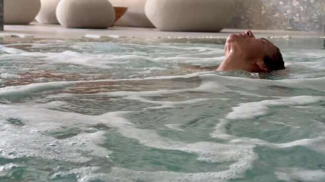 Luxurious spa moment featuring a woman enjoying hot thermal water in a jacuzzi, surrounded by gentle bubbles, focusing on wellness, relaxation, rejuvenation, and beauty during a serene