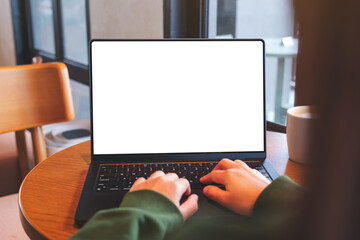 Mockup image of a woman working and typing on laptop computer with blank white desktop screen in...