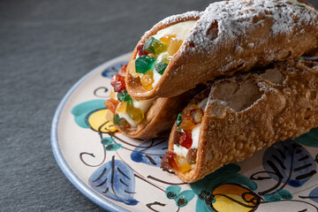 Traditional sicilian ricotta cannoli on a handmade decorated ancient plate closeup