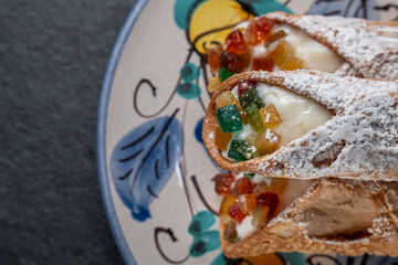 Traditional sicilian ricotta cannoli on a handmade decorated ancient plate closeup