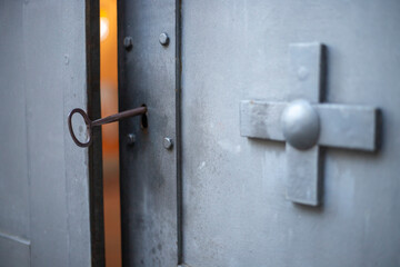 Gothic iron door ajar showcasing a timeless key and sacred cross symbol