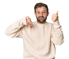 Studio portrait of young Hispanic male showing thumbs up and thumbs down, difficult choose concept