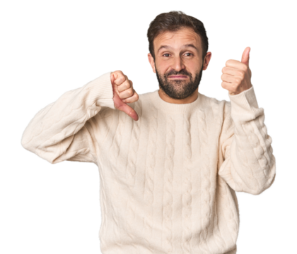 Studio portrait of young Hispanic male showing thumbs up and thumbs down, difficult choose concept