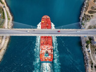 Aerial overhead view of a large cruide oil tanker passing under a bridge with car traffic