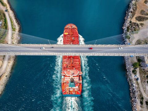 Aerial overhead view of a large cruide oil tanker passing under a bridge with car traffic