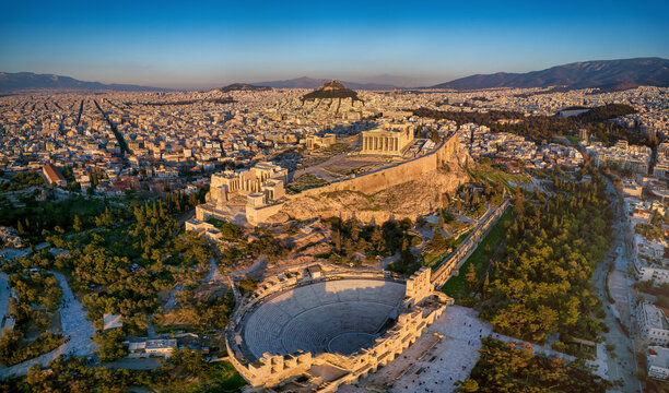 Panoramic aerial view of the Parthenon Temple and the Odeon of Herode theatre at the Acropolis of Athens, Greece, in golden sunset light