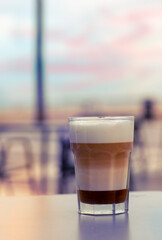caramel latte coffee in glass closeup photo on sea beach background