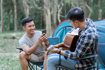 Fototapeta premium Happy Couple Enjoying a Relaxing Camping Trip in the Forest with a Tent and Guitar