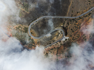Vue aérienne drone d’une route de montagne avec nuage brouillard et suivi de véhicule...