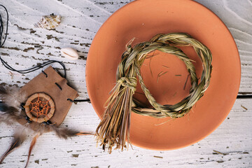Sweetgrass braid (Hierochloe odorata), also called vanilla grass, on a clay plate and medicinal...