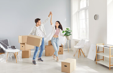 Excited homeowners, renters, happy to move new own flat, carrying boxes, married young couple enjoying moving into first house, man and woman couple feeling joy with relocation, dancing in joy