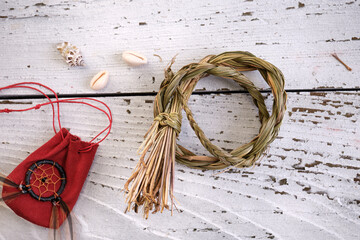 Sweetgrass braid (Hierochloe odorata), also called vanilla grass, and red medicinal pouch on old white wood. Overhead view.