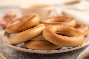 Homemade Ring Bagel with cup of coffee on brown concrete, side view, close up, selective focus.