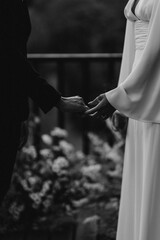 A romantic moment is captured as the bride and groom hold hands during their wedding ceremony surrounded by floral beauty