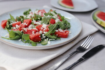 Watermelon and Arugula Salad with Feta Cheese on a Light Plate on Light Grey Background