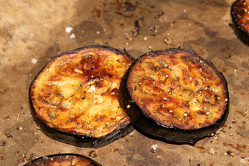 A roasted sliced seasoned aubergine eggplant courgette with salt and herbs cooked in the oven close up