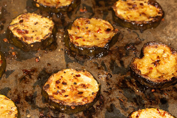 A roasted sliced seasoned aubergine eggplant courgette with salt and herbs cooked in the oven close up