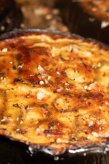 A roasted sliced seasoned aubergine eggplant courgette with salt and herbs cooked in the oven close up