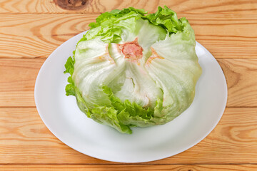 Head of fresh iceberg lettuce on dish on rustic table