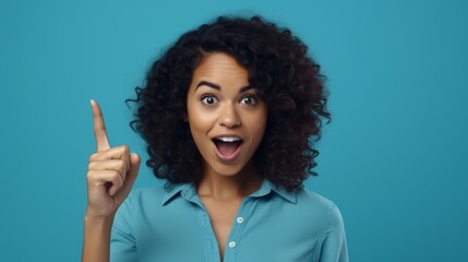 A joyful woman with curly hair gestures upward, showcasing enthusiasm against a vibrant blue backdrop. Her expression radiates excitement and energy in this cheerful moment