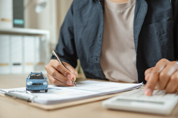 Man signing car insurance on paperwork assurance. Buying or selling new vehicle. Ownership for new...