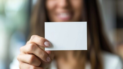 business woman holding a blank card, A beautiful woman holds a blank business card. Card is in focus the camera. Woman is in the background. She smiles naturally at the camera. marketing photograph. 