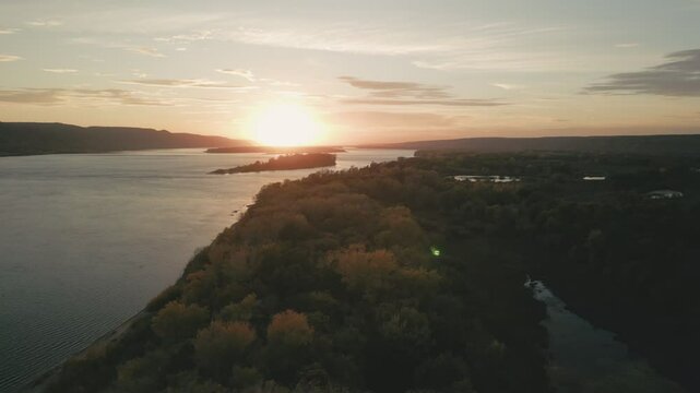 Sun setting over river and forest landscape