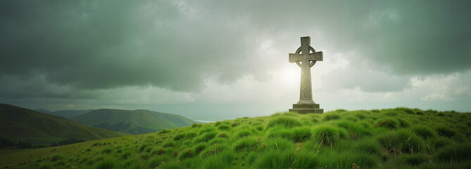 Celtic cross on a green hill under cloudy skies