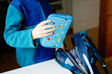 School kid boy getting ready in the morning for school. Healthy child filling satchel with books,...