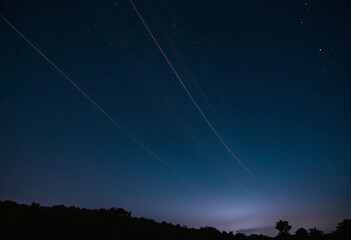 Fototapeta premium Captivating night sky with streaks of light in a dark landscape showcasing the beauty of the cosmos