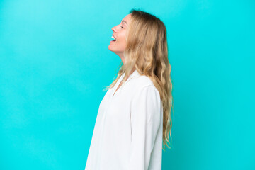Young Russian woman isolated on blue background laughing in lateral position