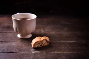 Cantuccini (Italian cookies) and a cup of coffee on dark wooden background. Close up..