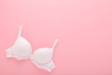 New white lace bra on light pink table background. Pastel color. Female casual underwear. Closeup....