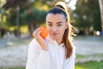 Young pretty brunette woman holding an orange