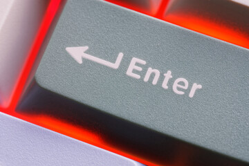 Close-up view of a computer keyboard's enter key illuminated by red backlighting. Photo
