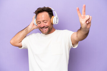 Fototapeta premium Middle age caucasian man isolated on purple background listening music and singing