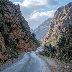Fototapeta premium Winding mountain road through a rocky gorge with distant peaks under a cloudy sky