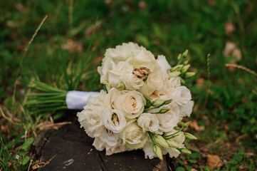 Elegant White Rose Bouquet with Wedding Rings on Green Grass