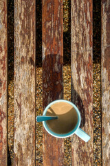a cup of coffee on wooden bench in shade of morning sunrise with tea spoon looked like  7 o'clock's...