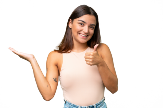 Young caucasian woman isolated on green chroma background holding copyspace imaginary on the palm to insert an ad and with thumbs up
