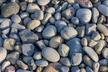 Smooth, colorful pebbles create a natural mosaic on a tranquil riverbank in the soft evening light
