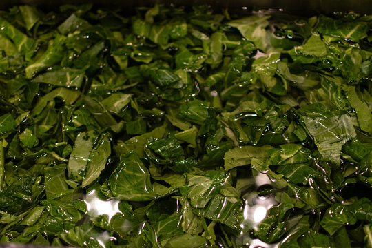 Washing fresh greens in a sink of water. The greens have already been chopped and are soaking. 