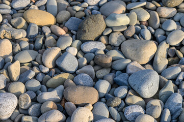 Stones and pebbles creating a textured mosaic on a serene beach at sunset