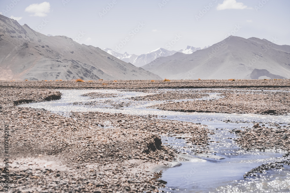 Canvas Prints High-mountain river flows in a valley against the background of rocky mountain ranges in the Tien Shan mountains in the Pamirs in Tajikistan, landscape for background